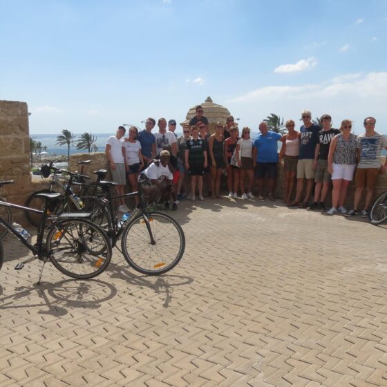 A large group of people posing next to bicycles